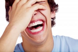 teenage boy laughing covering eye