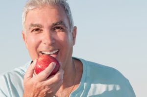 smiling mature man eating apple