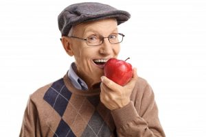 older man smiling holding apple