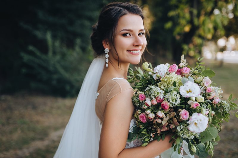 Bride smiling in wedding dress with bouquet